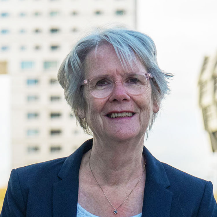 Foto van Dineke Smit, Directeur en onderzoeker bij Stichting Steunpunt Zelfregie en Herstel. Op de achtergrond architectuur van Almere.