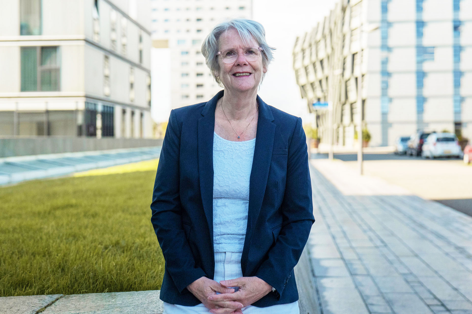 Foto van Dineke Smit, Directeur en onderzoeker bij Stichting Steunpunt Zelfregie en Herstel. Op de achtergrond architectuur van Almere.